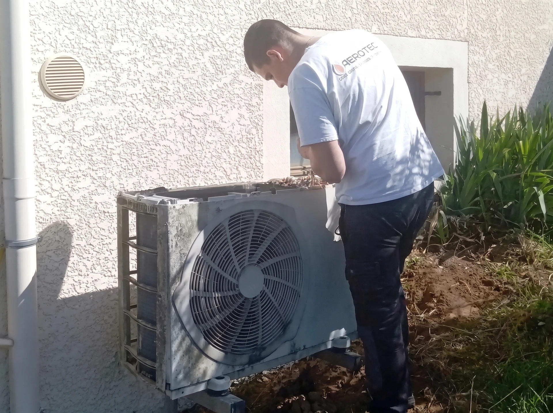 Un technicien travaillant sur la climatisation ou la pompe à chaleur d'une unité extérieure