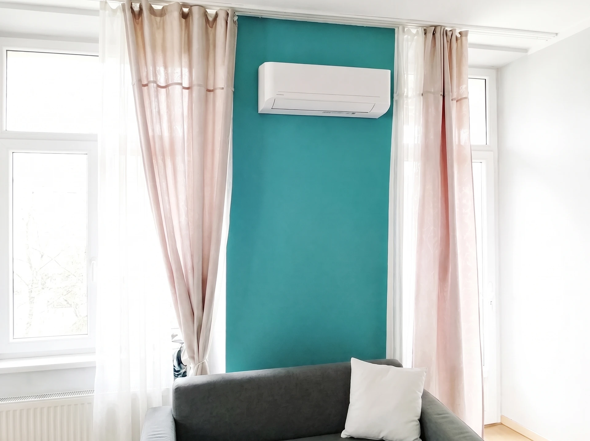 Technicien en tenue professionnelle bleu marine inspectant une pompe à chaleur air-air murale installée en intérieur lumineux, examinant l'unité avec attention tout en tenant un carnet ou un appareil de diagnostic, posture sereine et confiante.