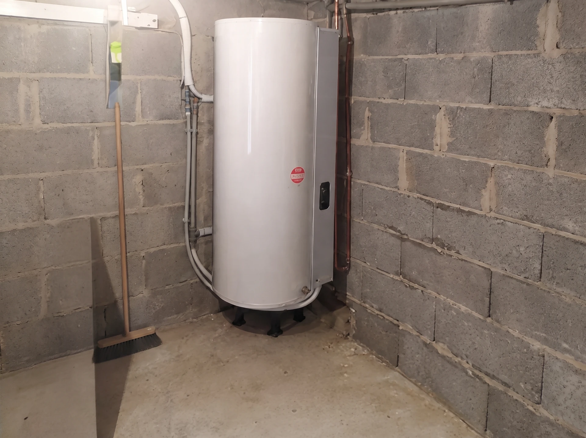 Plombier professionnel effectuant la maintenance d'un chauffe-eau électrique dans un sous-sol résidentiel